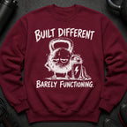 Maroon sweatshirt with graphic of a sweaty, sad kettlebell and the text "Built Different Barely Functioning."