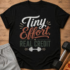Black t-shirt with "Tiny Effort, Real Credit" text and dumbbell graphic.