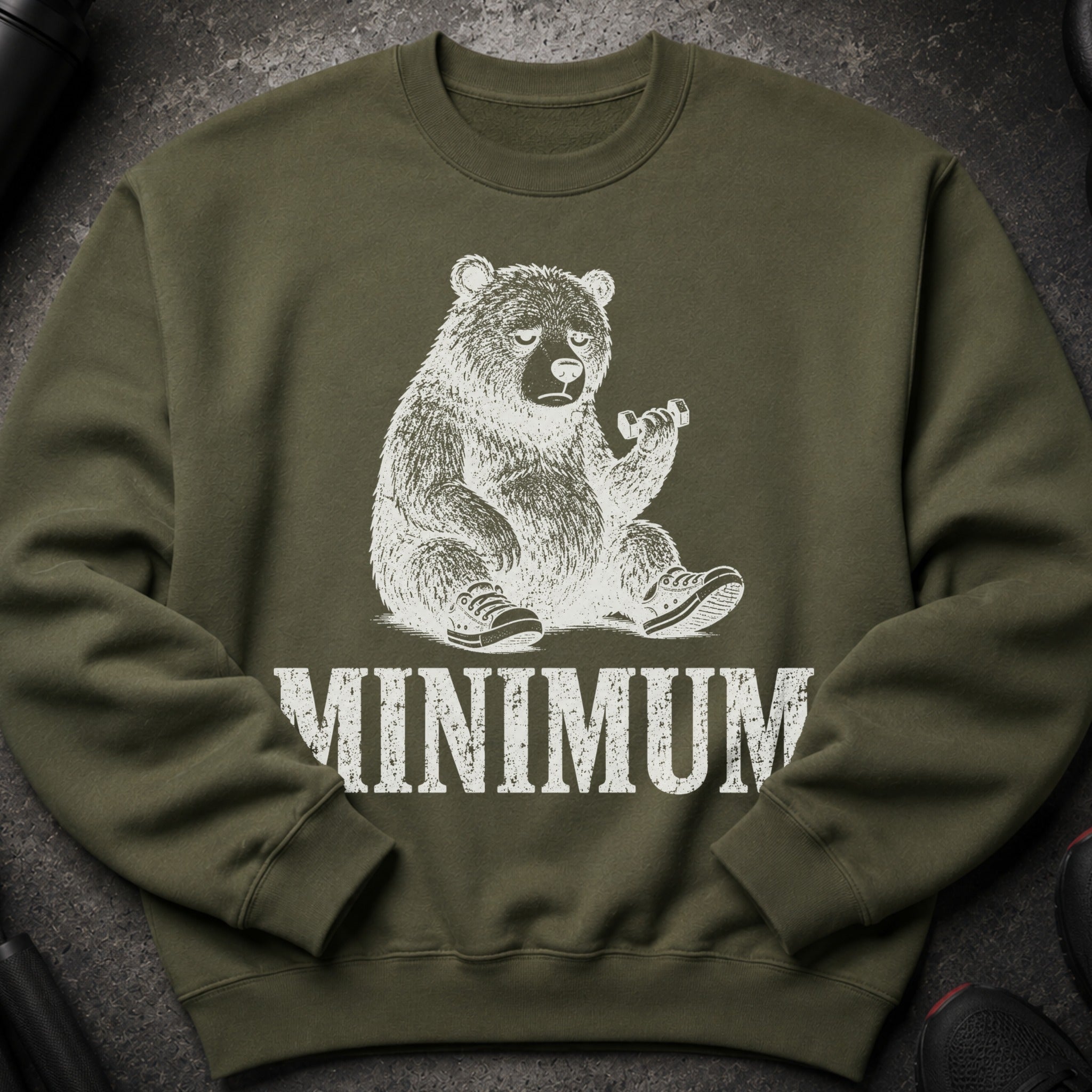 Olive green sweatshirt with a distressed white graphic of a tired bear holding a dumbbell, and the word MINIMUM.