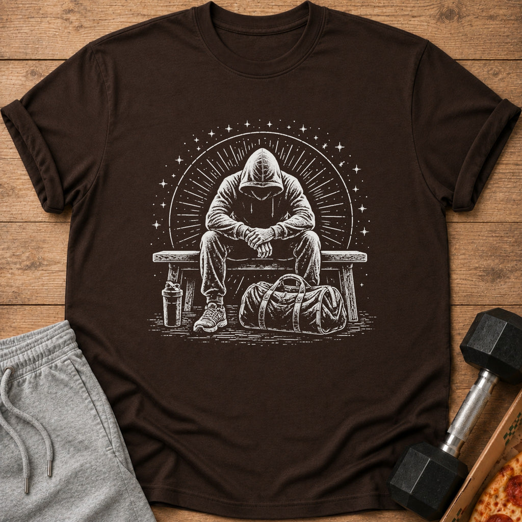 Brown t-shirt with a white graphic of a person in a hoodie sitting on a bench with gym bag.