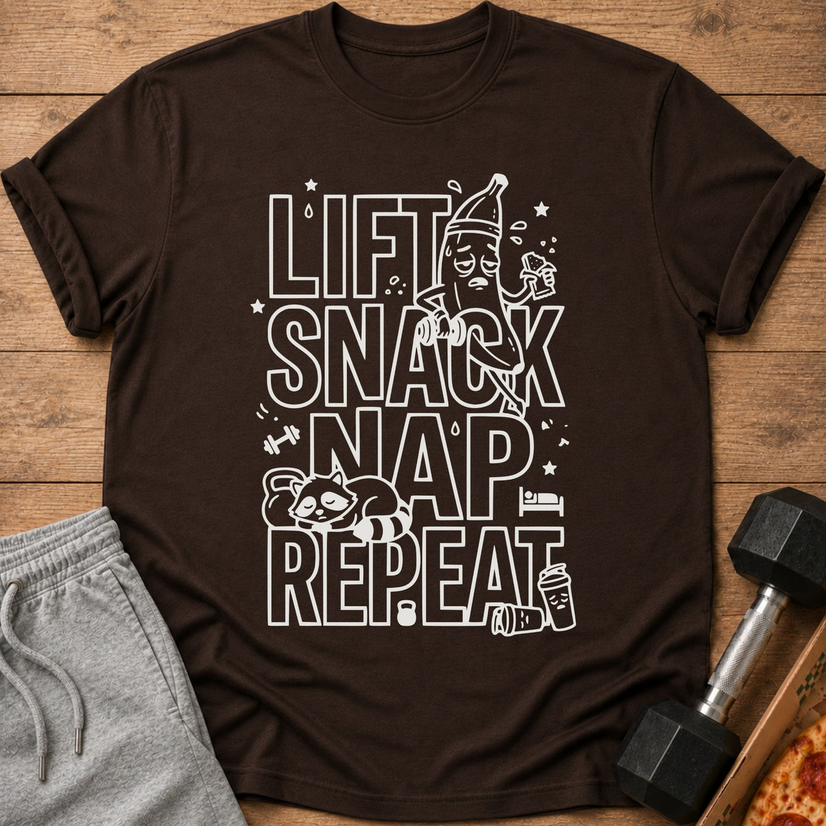 Brown t-shirt with "Lift Snack Nap Repeat" graphic, a tired banana, and a sleeping raccoon.