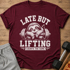 Maroon t-shirt with white text "LATE BUT LIFTING COUNTS THE SAME" and sleepy sloth.