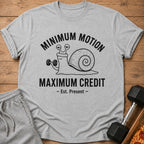Grey t-shirt with a snail lifting a dumbbell and text "Minimum Motion Maximum Credit".