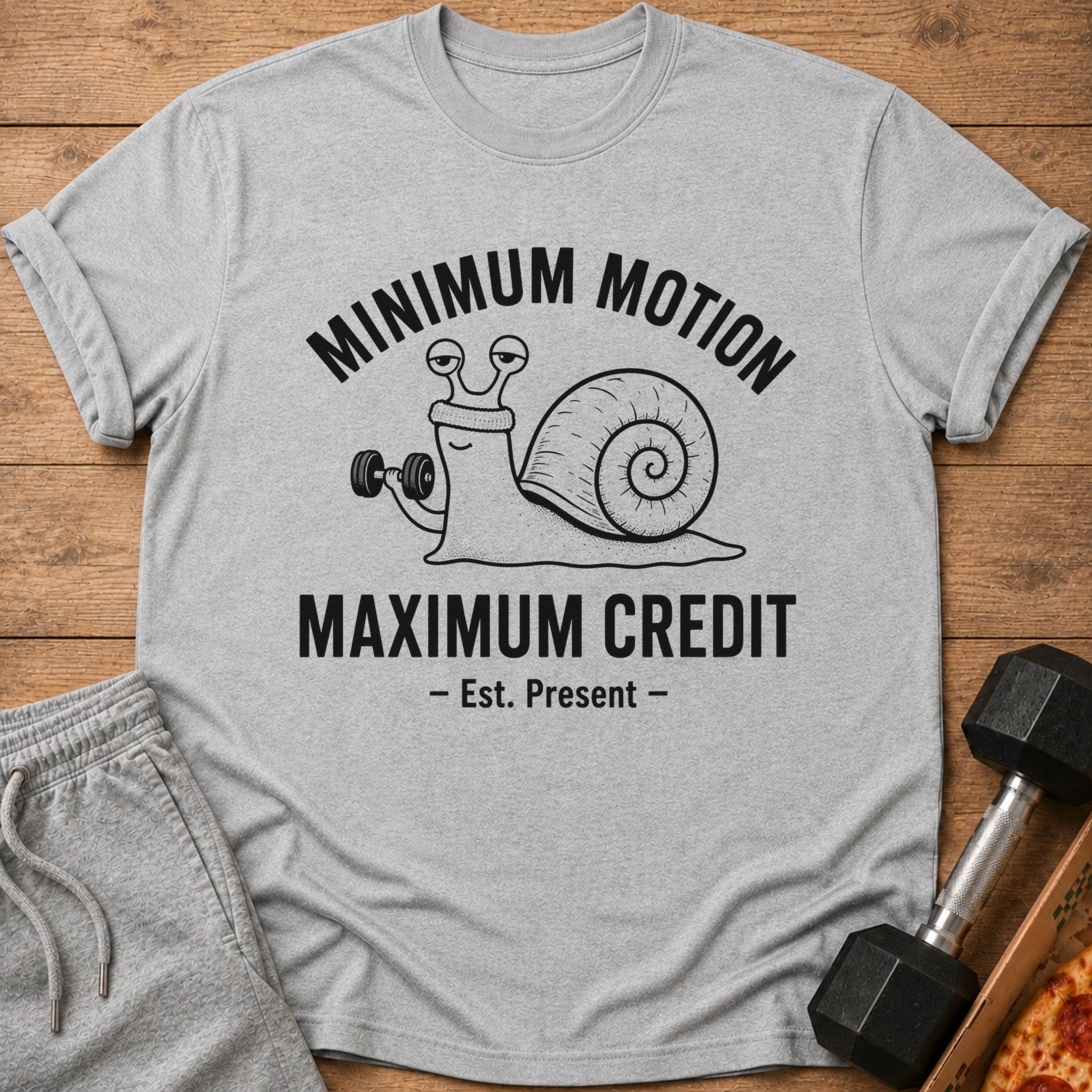 Grey t-shirt with a snail lifting a dumbbell and text "Minimum Motion Maximum Credit".