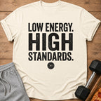 Cream t-shirt with "LOW ENERGY. HIGH STANDARDS." text and a weight plate graphic.