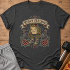 Muscular frog with barbell, banner text "HEAVY FEELINGS", roses, and a kettlebell.