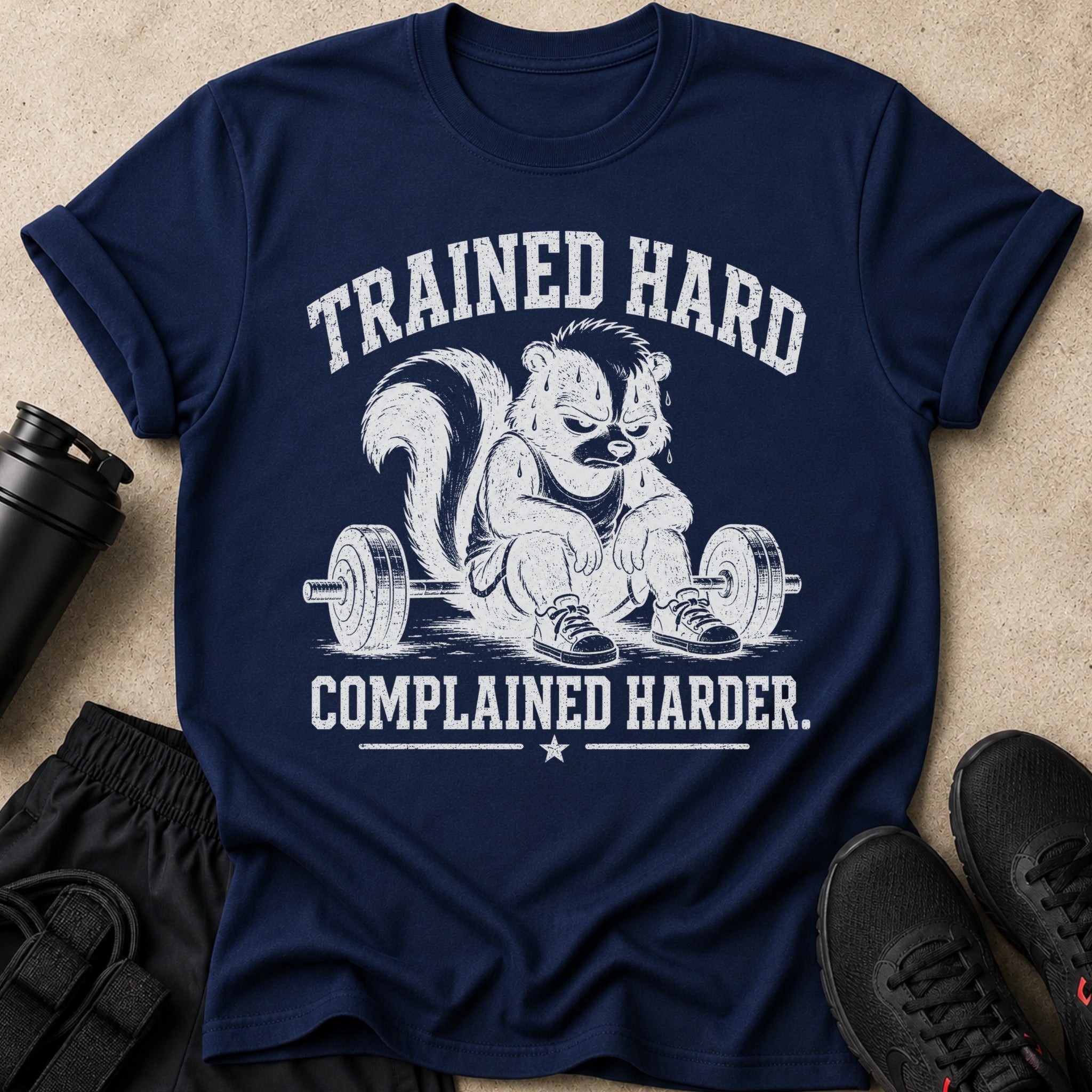Navy t-shirt with graphic of a skunk sitting by a barbell, text reads "TRAINED HARD COMPLAINED HARDER."