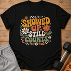 Black t-shirt with retro text "Showed Up Still Counts" and floral graphics.