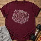 Maroon t-shirt with dinosaur skeleton and barbell graphic, with shorts and weights.