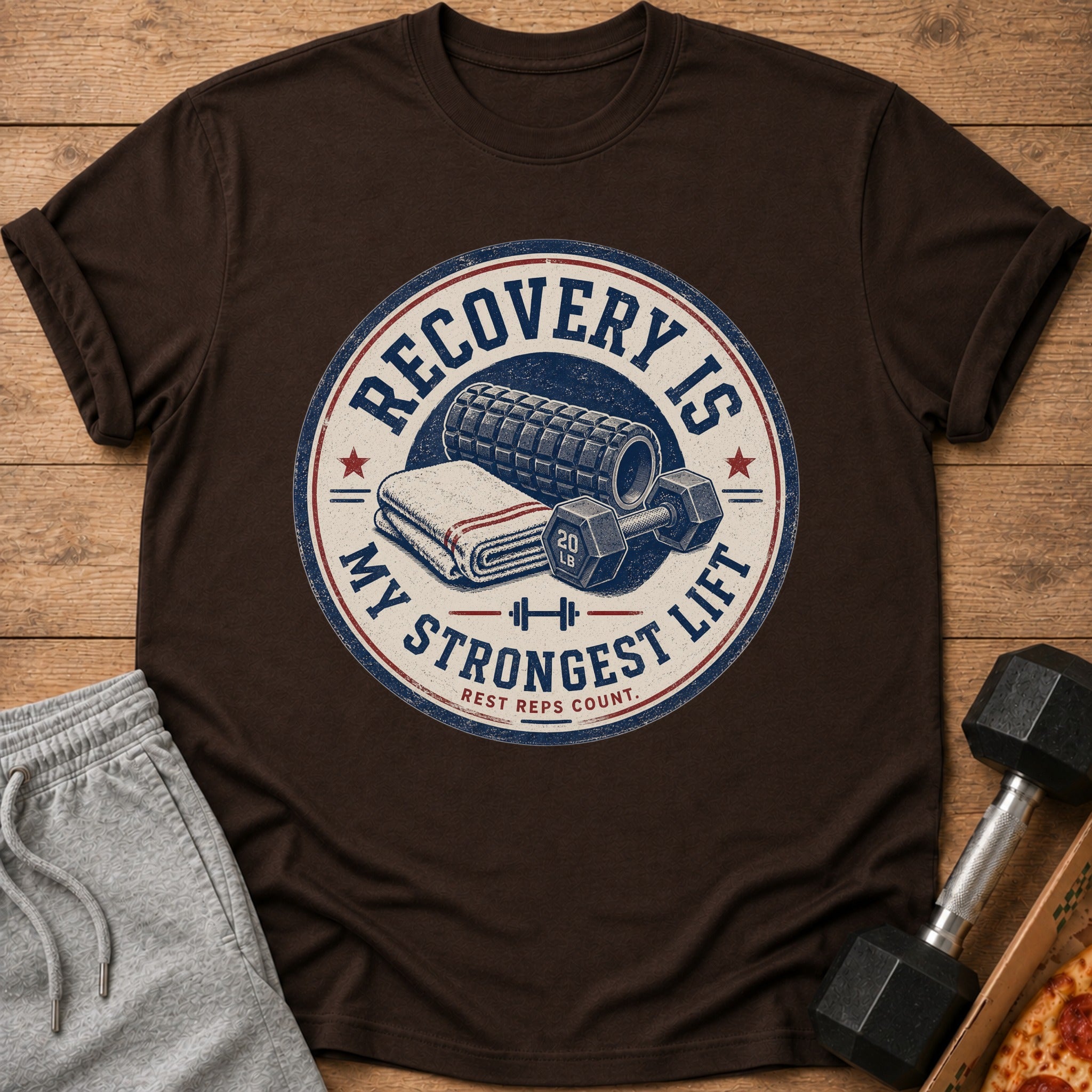 Brown t-shirt with circular graphic: "Recovery is My Strongest Lift. Rest Reps Count."
