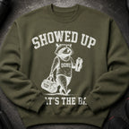 Green sweatshirt with distressed graphic of a raccoon holding a gym bag and shaker.