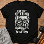 Black t-shirt with "I'm not getting stronger, I'm just developing trust issues with stairs."