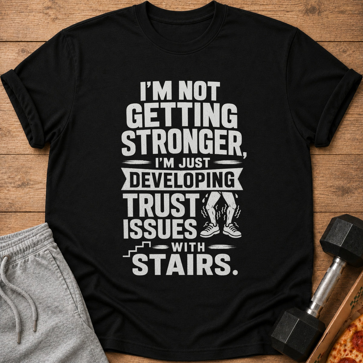 Black t-shirt with "I'm not getting stronger, I'm just developing trust issues with stairs."