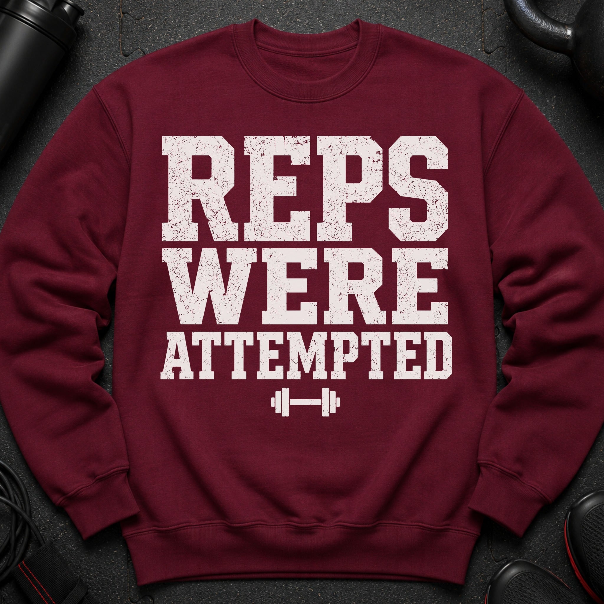 Maroon sweatshirt with graphic text "REPS WERE ATTEMPTED" and barbell.