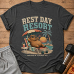 Dark grey t-shirt with "Rest Day Resort" text and a capybara relaxing by a pool at sunset.