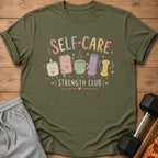 Green t-shirt with "Self-Care Strength Club" text and cartoon characters.
