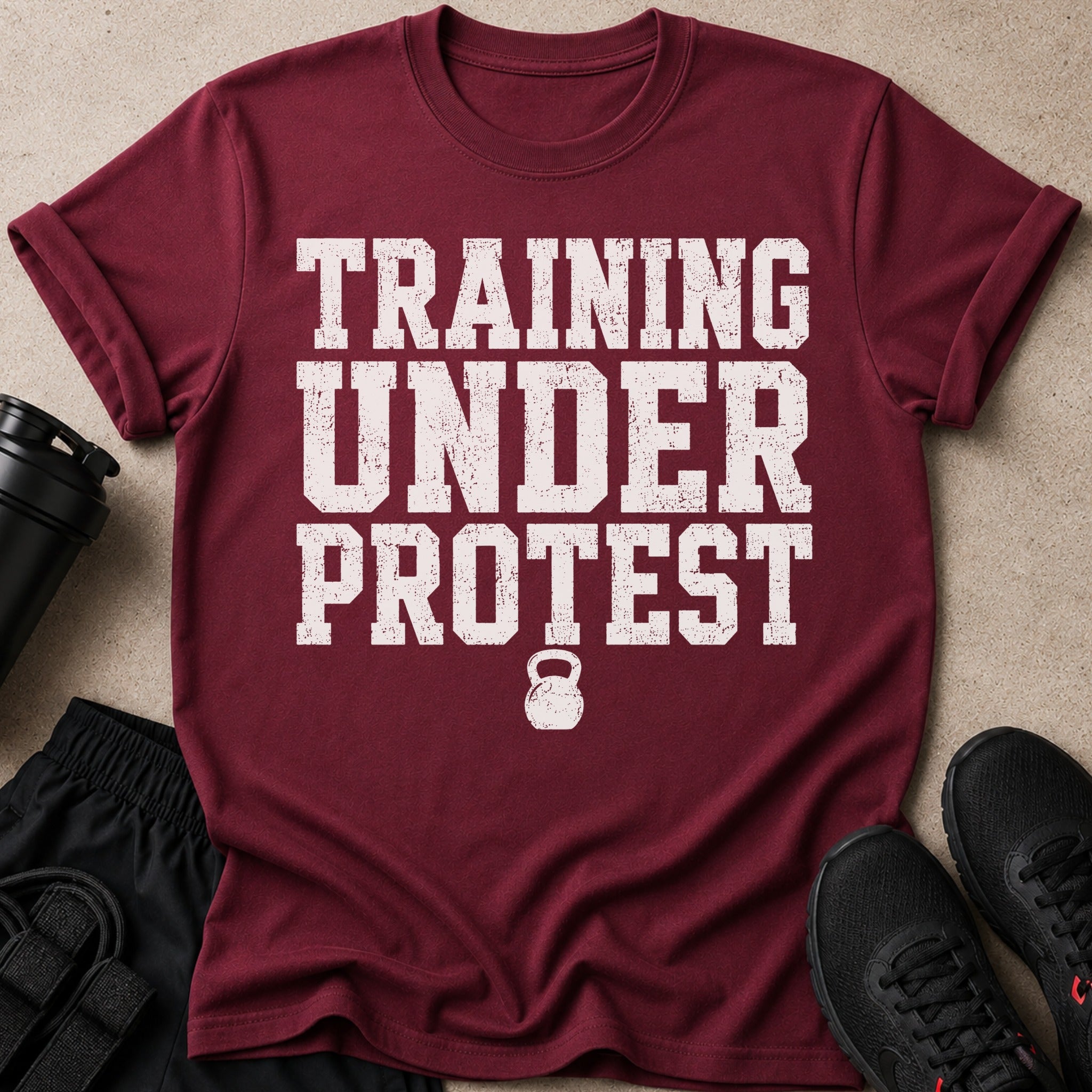 Maroon t-shirt with distressed white text "TRAINING UNDER PROTEST" and kettlebell graphic.