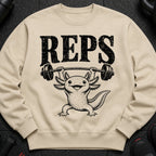 Axolotl lifting barbell with text REPS printed on a beige sweatshirt.