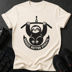 Cream t-shirt with a black graphic of a sloth hanging from a bar, with text "SNOOZE BUTTON ATHLETE".