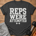 Dark grey t-shirt with white text "REPS WERE ATTEMPTED" and a dumbbell icon.