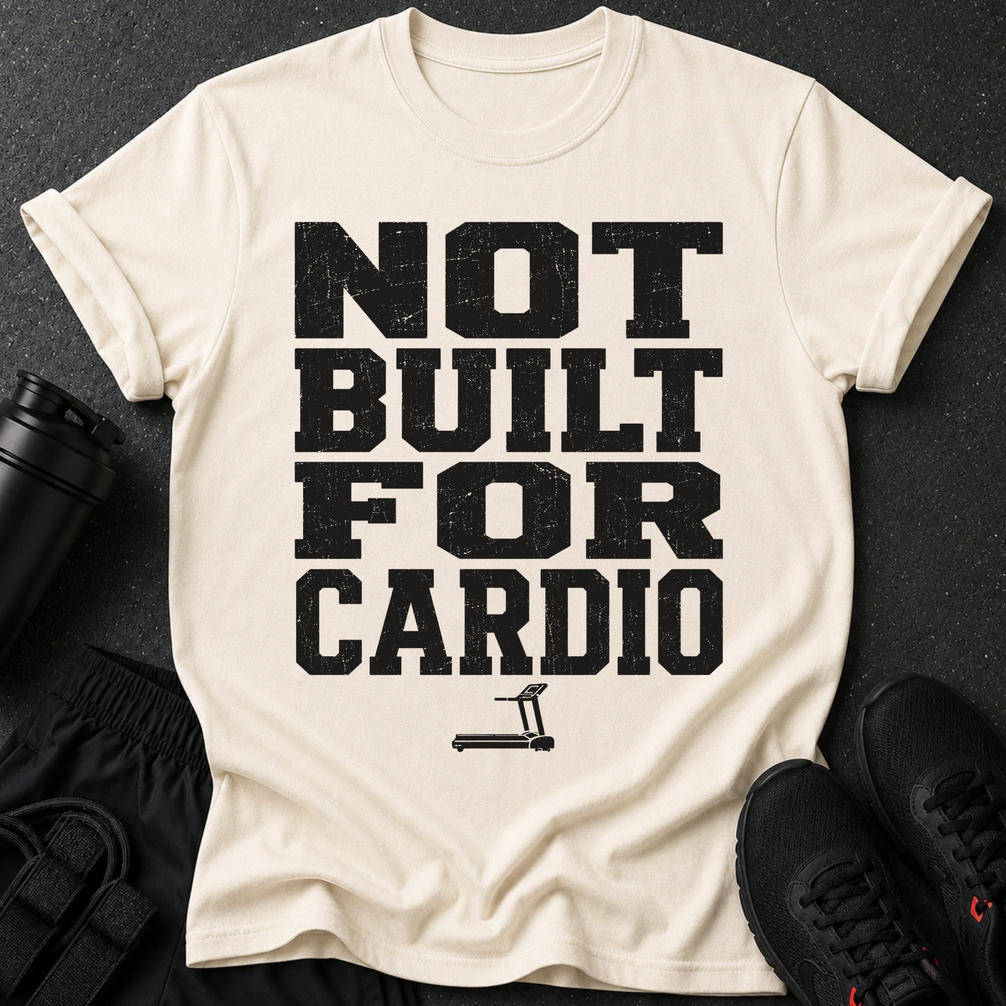 Cream t-shirt with black text "NOT BUILT FOR CARDIO" and treadmill graphic.