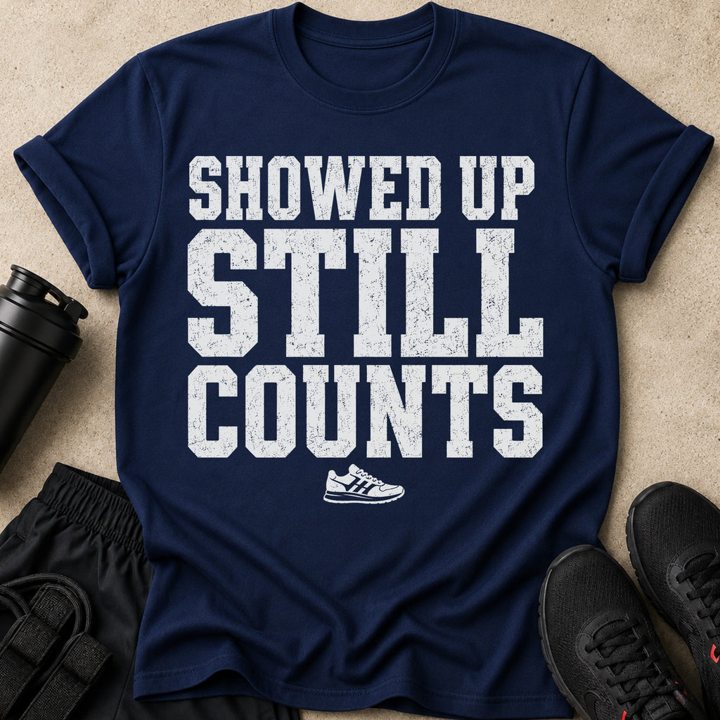Navy t-shirt with white distressed text "SHOWED UP STILL COUNTS" and a sneaker graphic.