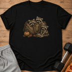 Three raccoons peek out of a duffel bag with a pumpkin and leaves.