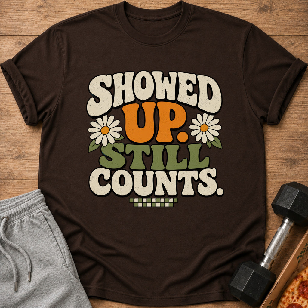 Brown t-shirt with "SHOWED UP. STILL COUNTS." text, daisies, and checkered pattern.