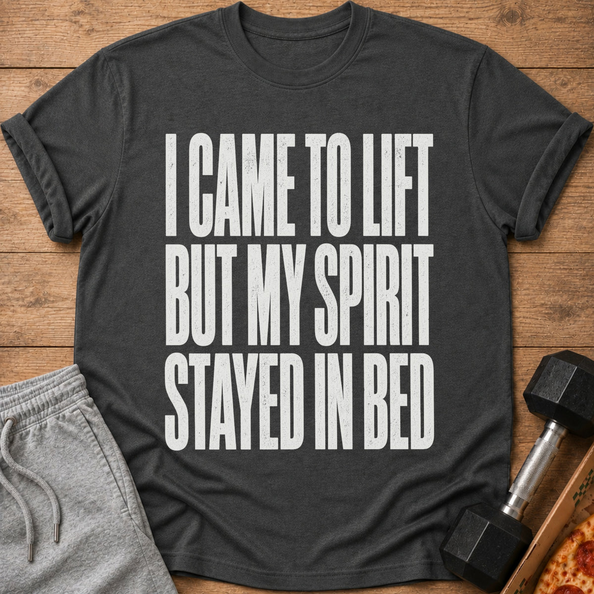 Dark gray t-shirt with white text "I CAME TO LIFT BUT MY SPIRIT STAYED IN BED".