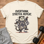 Overthink. Stretch. Repeat. graphic on a cream t-shirt with a tangled possum.