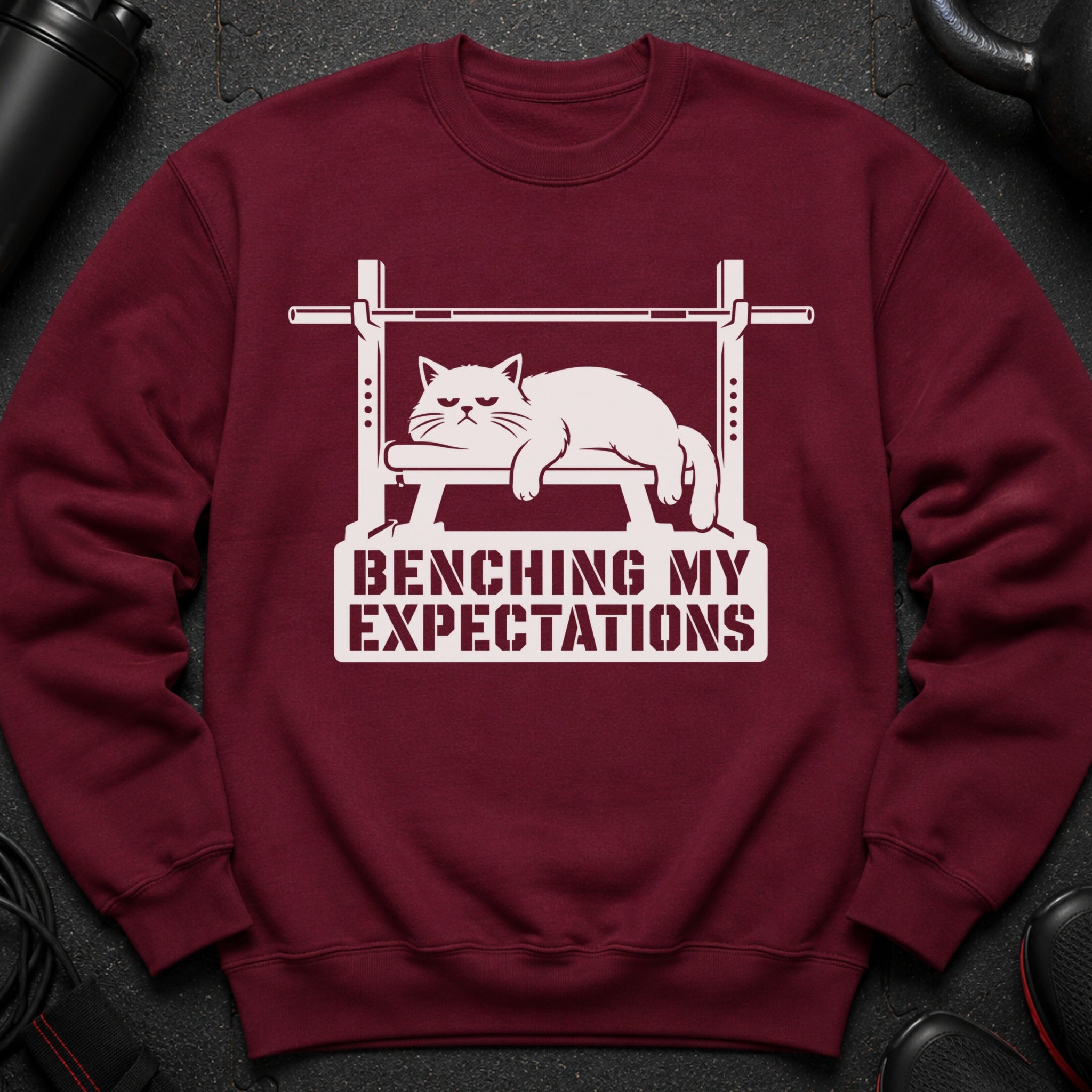 Maroon sweatshirt with a white graphic of a cat on a bench press and text.