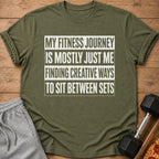 Olive green t-shirt with text "My fitness journey is mostly just me finding creative ways to sit between sets."
