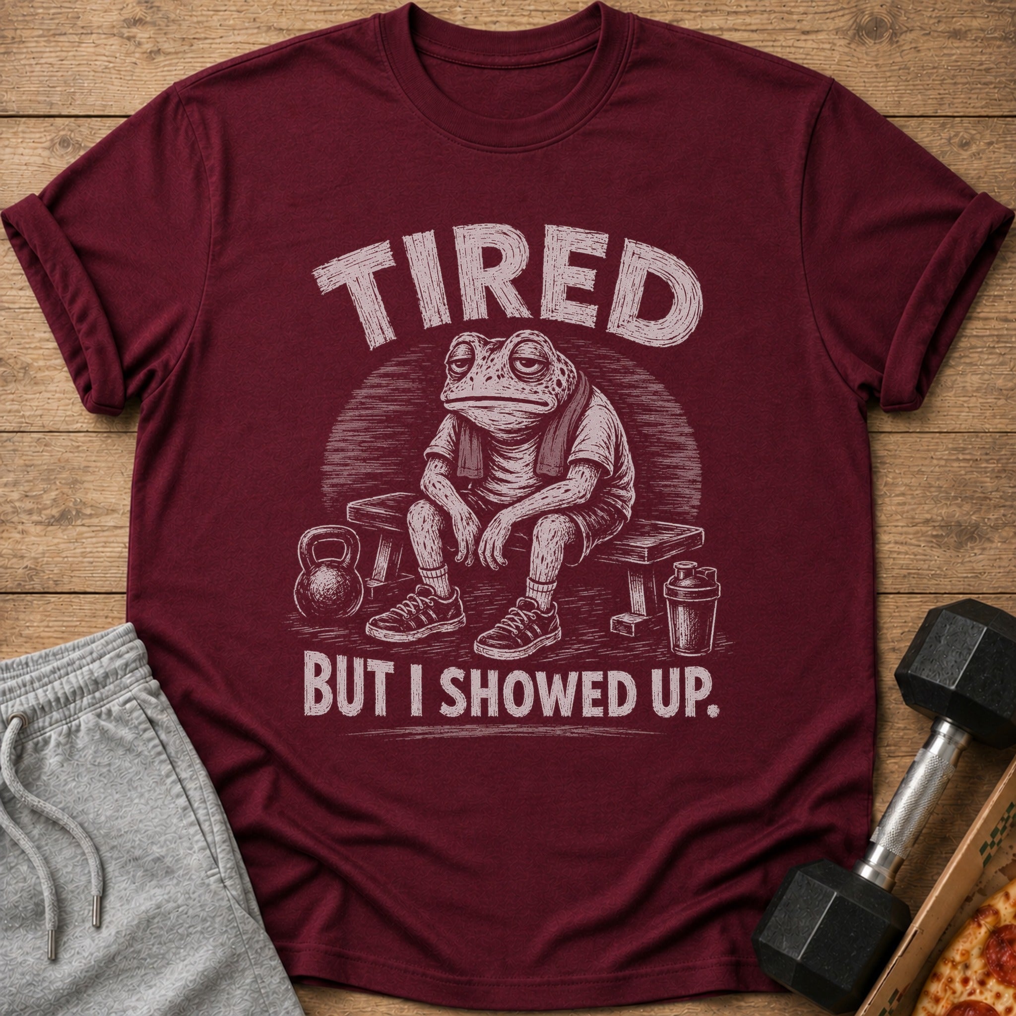 T-shirt with a tired frog lifting weights and the text "TIRED BUT I SHOWED UP."