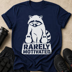 Navy t-shirt with white graphic of a raccoon holding kettlebells and text "RARELY MOTIVATED".