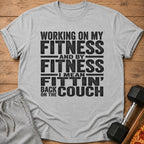 Grey t-shirt with "Working on my fitness and by fitness I mean fittin' back on the couch" text.
