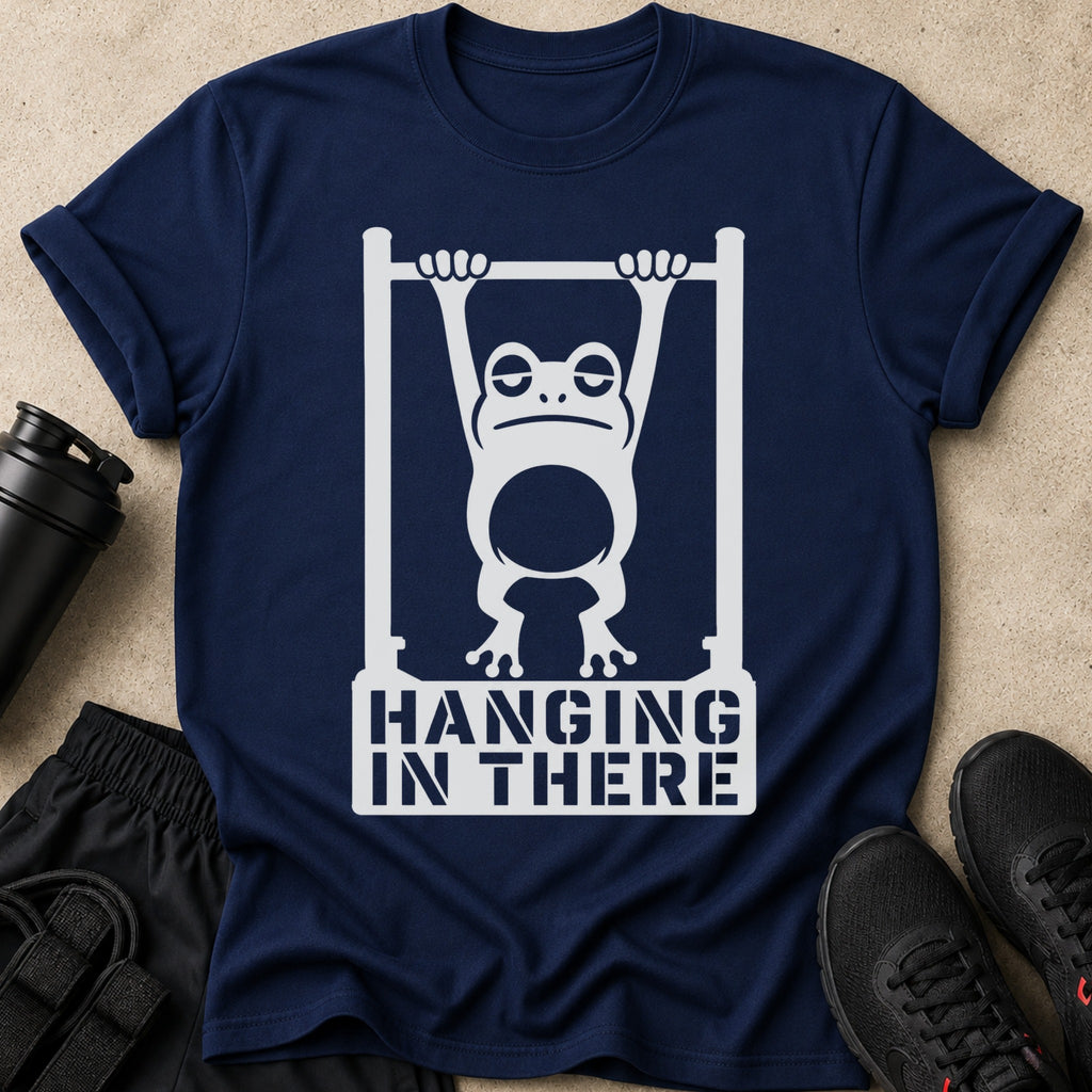 Navy t-shirt with white graphic of a tired frog hanging from a bar, text reads "HANGING IN THERE."