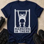 Navy t-shirt with white graphic of a tired frog hanging from a bar, text reads "HANGING IN THERE."