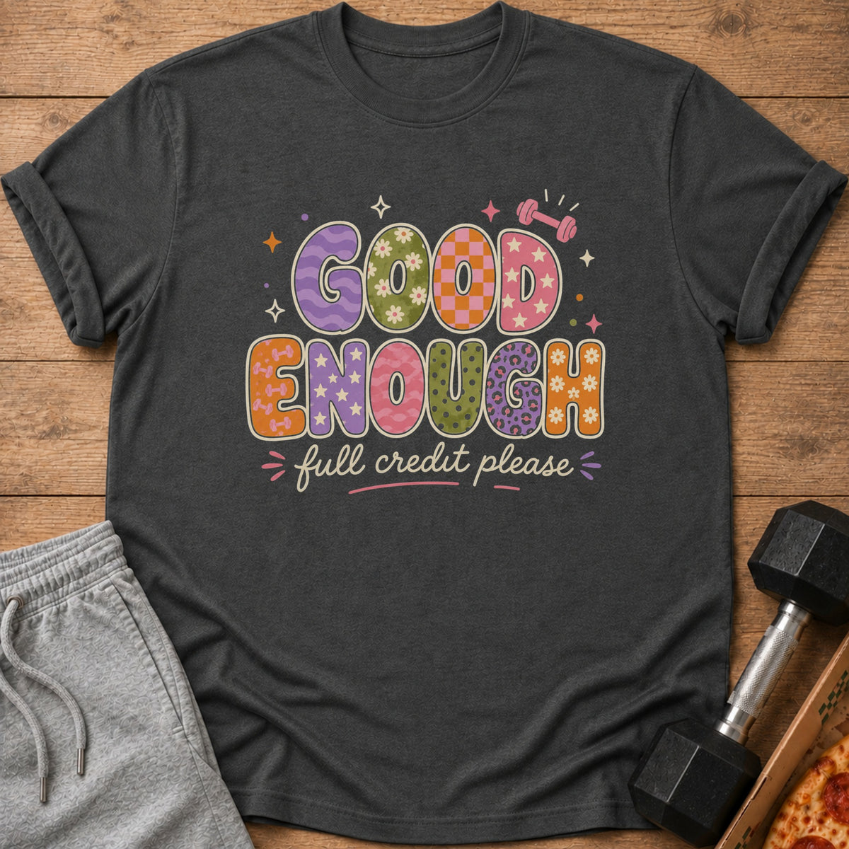 Dark t-shirt with "GOOD ENOUGH full credit please" text and playful graphics.