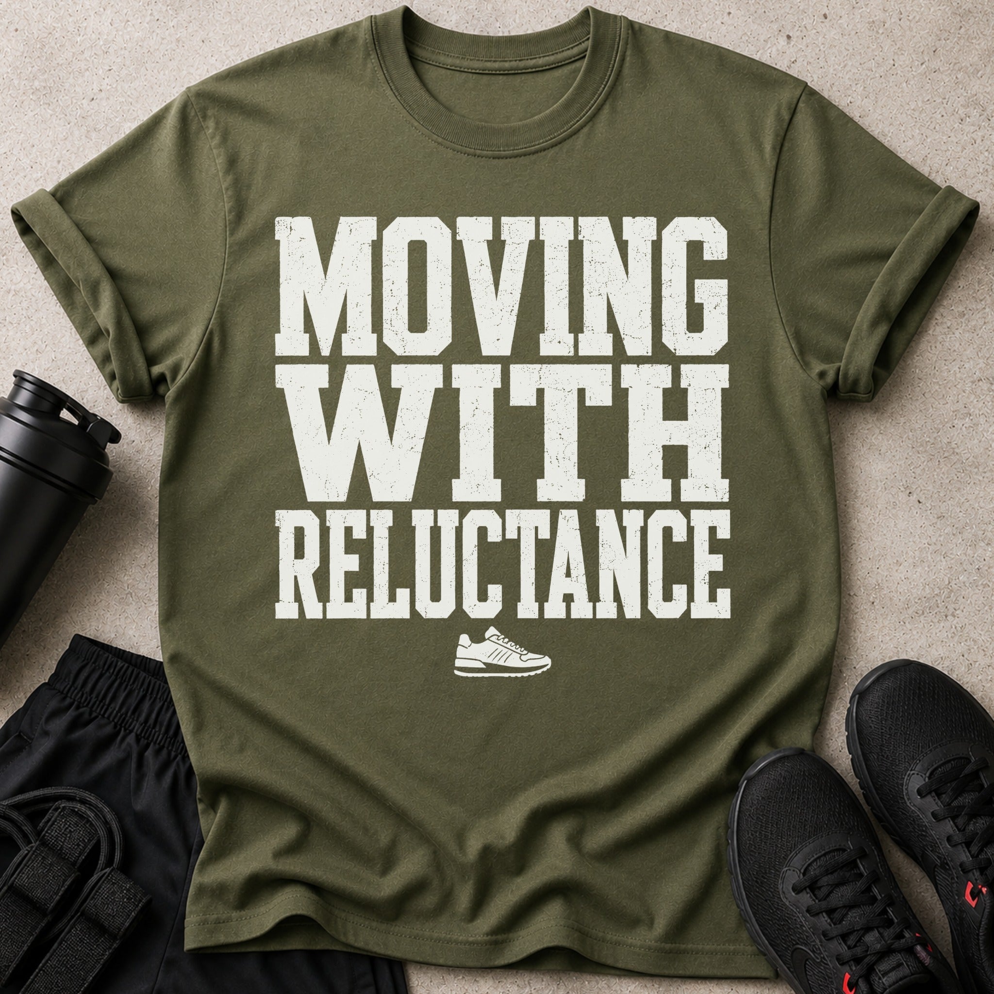 Olive green t-shirt with white distressed text: "MOVING WITH RELUCTANCE" and a sneaker graphic.