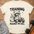 T-shirt graphic of a tired raccoon holding coffee, with dumbbells and pizza.