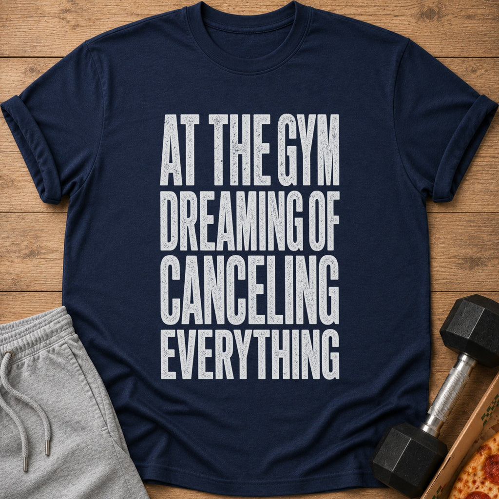 Navy t-shirt with white text reading "AT THE GYM DREAMING OF CANCELING EVERYTHING".