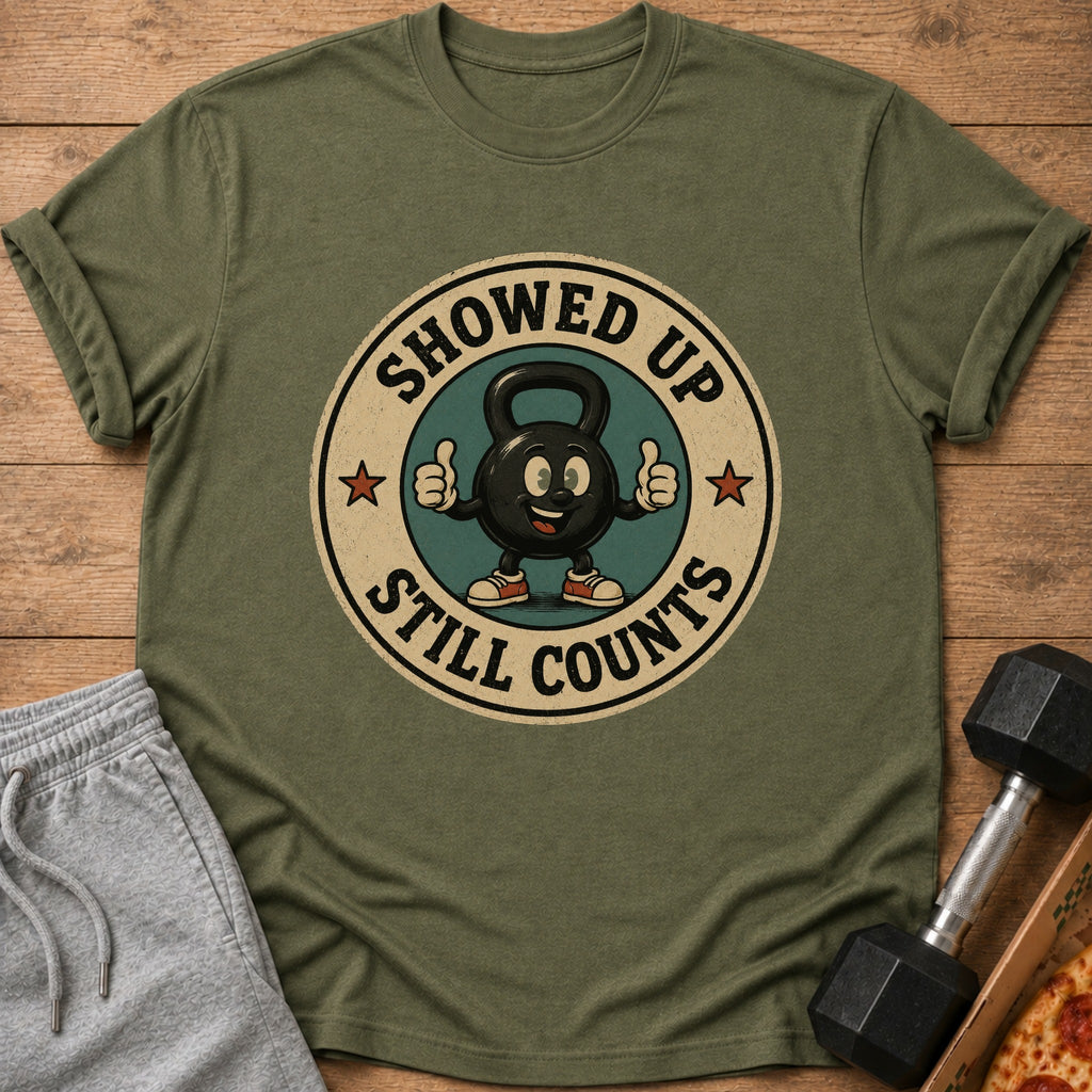 Green t-shirt with a cartoon kettlebell giving thumbs up and text "SHOWED UP STILL COUNTS".