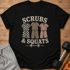 Black t-shirt with "Scrubs & Squats" text, three illustrated scrub sets, and a barbell.