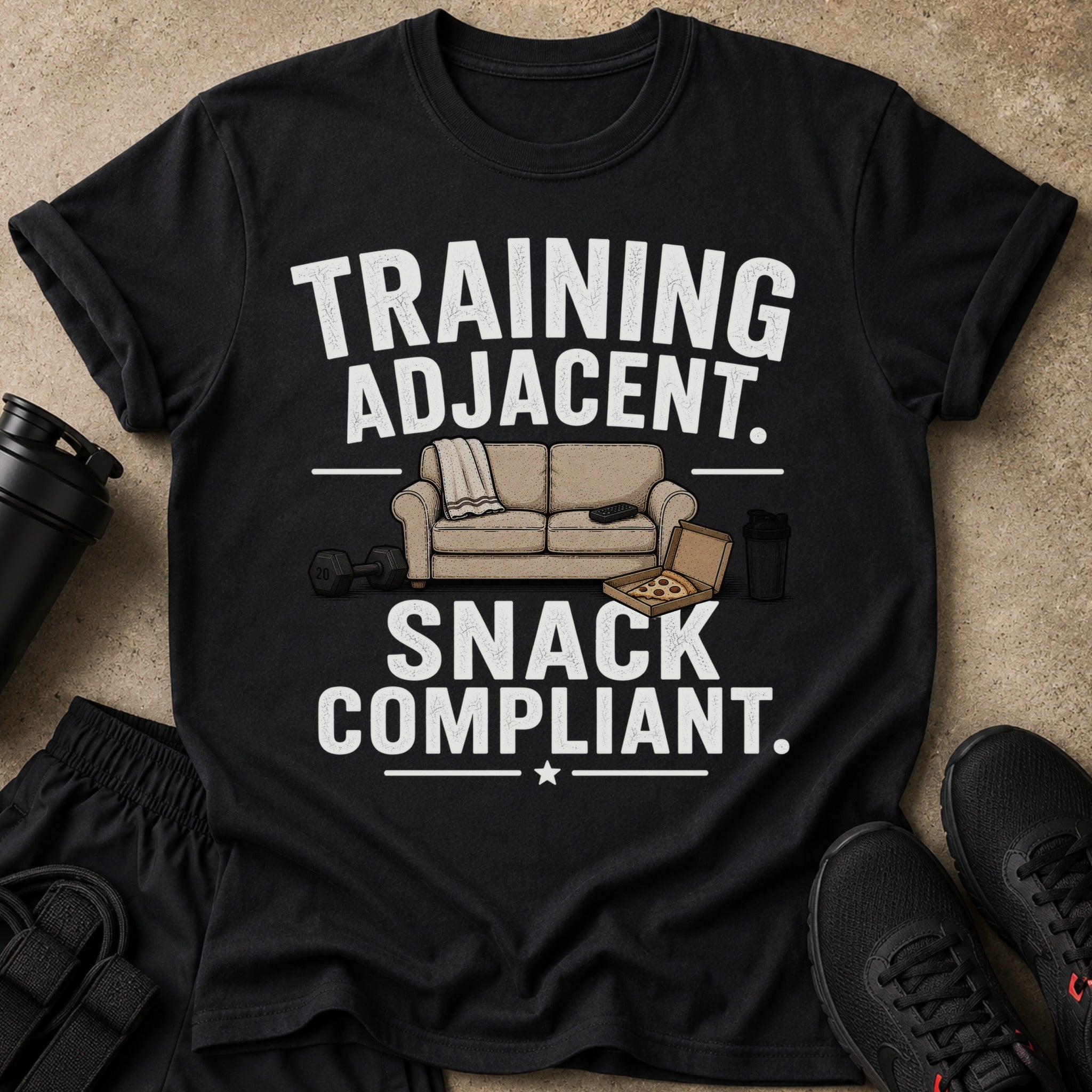 Black t-shirt with "TRAINING ADJACENT. SNACK COMPLIANT." text and couch illustration.