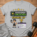 Grey t-shirt with pixelated "Achievement Unlocked Showed Up" graphic and stats.