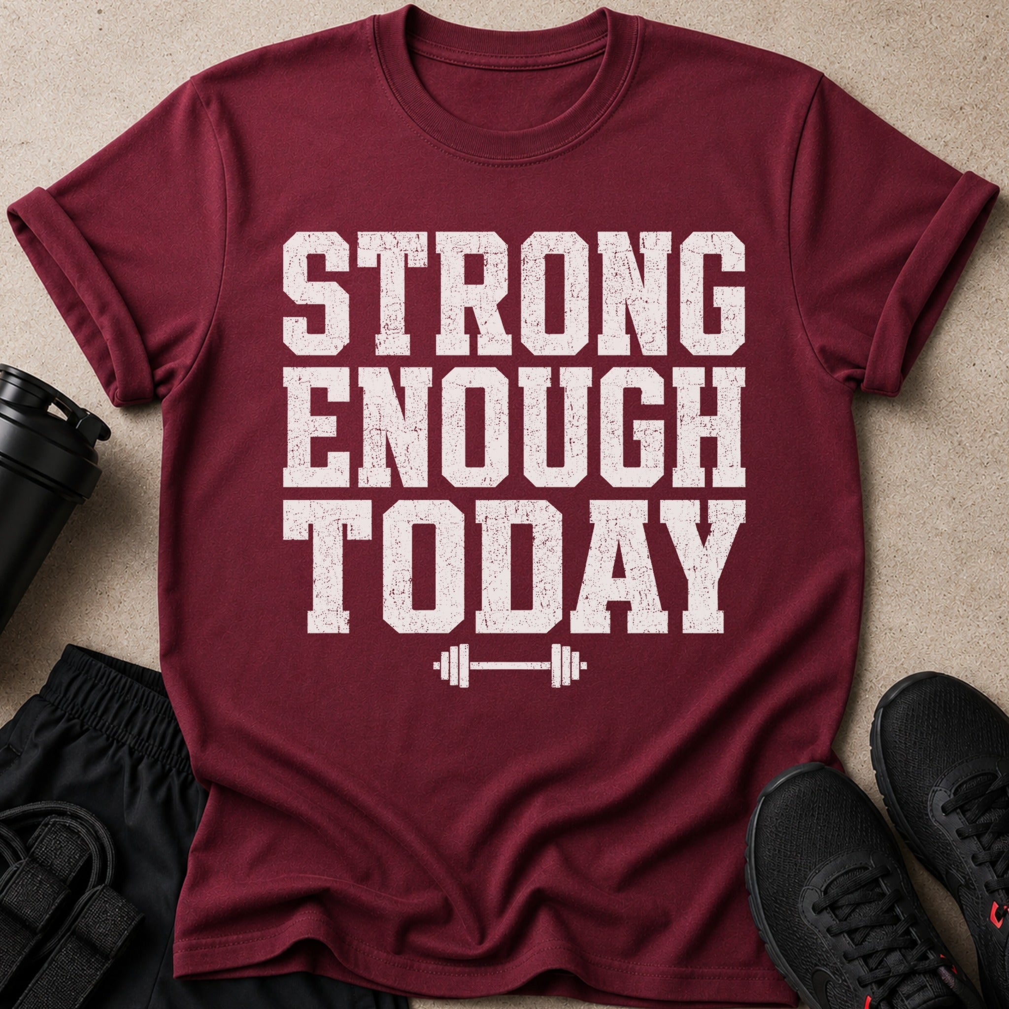 Maroon t-shirt with distressed white text reading "STRONG ENOUGH TODAY" and a barbell graphic.