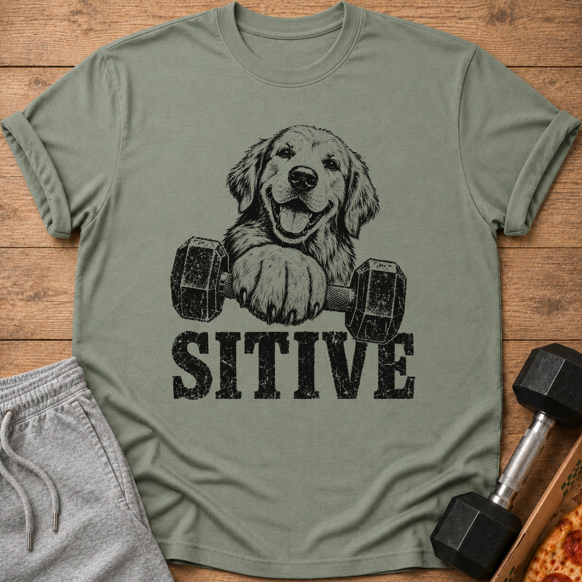 Green t-shirt with a black graphic of a golden retriever holding dumbbells and the word "SITIVE".