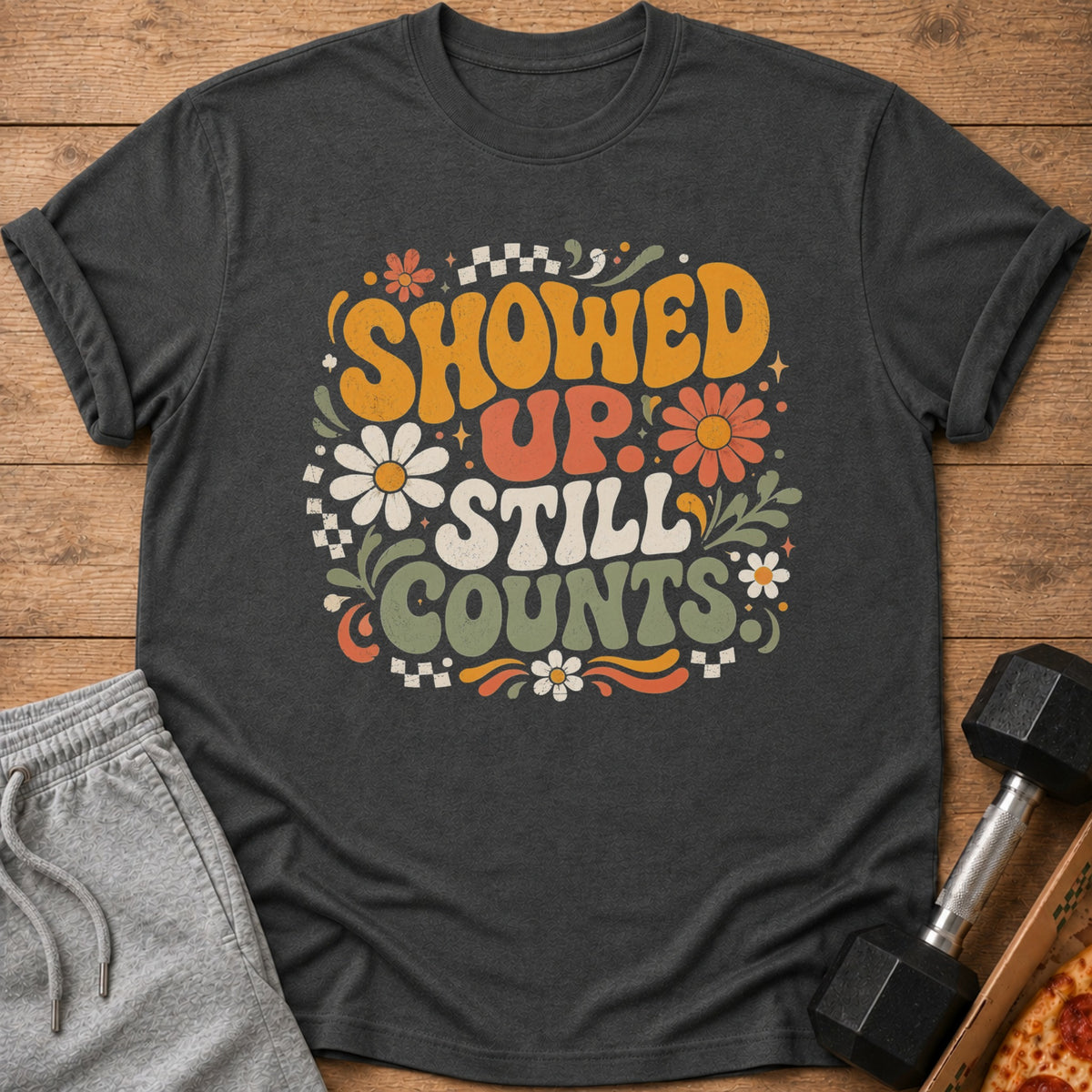 Dark grey t-shirt with vintage style text "SHOWED UP STILL COUNTS" and floral graphics.