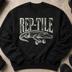 Black sweatshirt with a distressed white graphic of an alligator lifting a dumbbell, text reads REP-TILE.