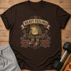 Brown t-shirt with frog lifting barbell, roses, and "Heavy Feelings" text.